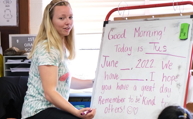 First grade teacher talking to students in front of classroom