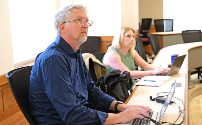 Faculty Academy - Sean Goodlett lead at table with laptop 