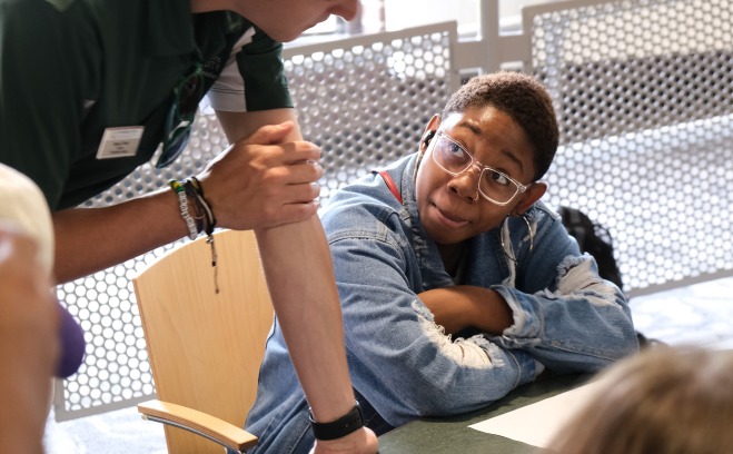 Student sitting at table listening to orientation leader