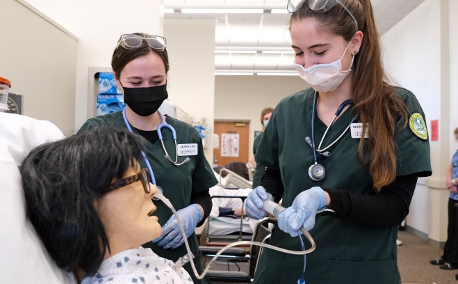 Nursing students in lab pushing a line into patients nose