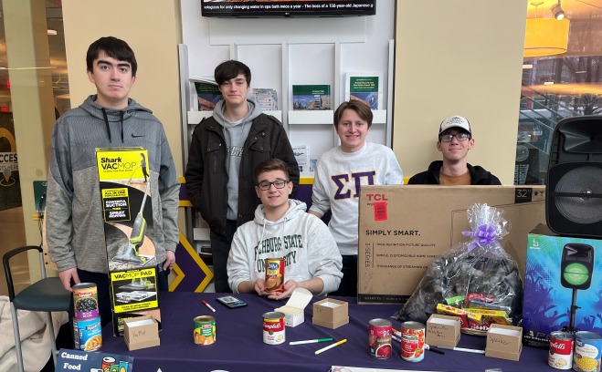 Fraternity brother at table in Hammond collecting can goods for Falcon Bazaar