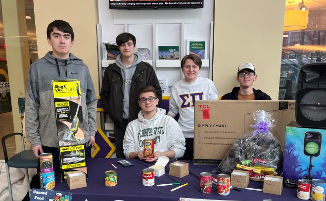 Fraternity brother at table in Hammond collecting can goods for Falcon Bazaar