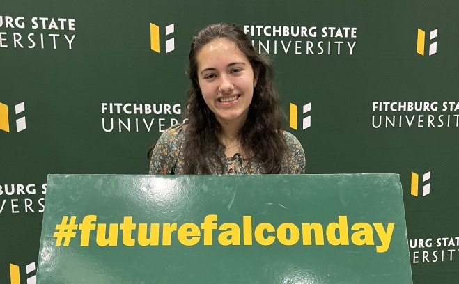 Female student at future falcon day with sign in front of backdrop