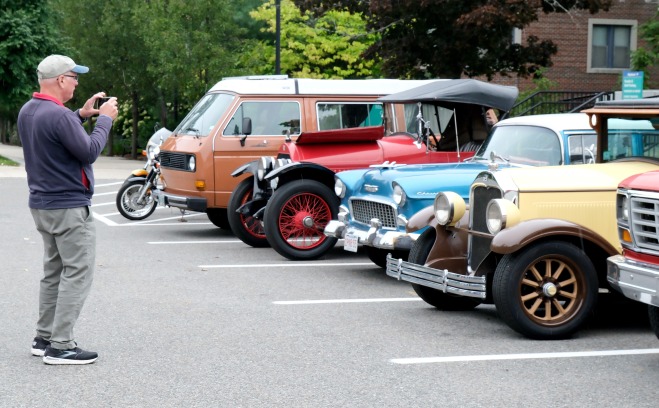 Alumni taking photo of cars at the car show in front of Mazzaferro