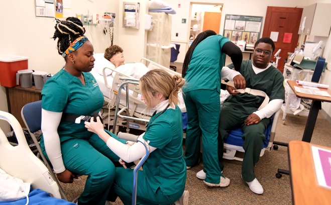 Nursing students in patient transfer lab preparing each other