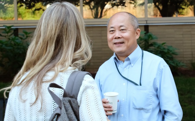 Hong Yu smiling outside talking to colleague