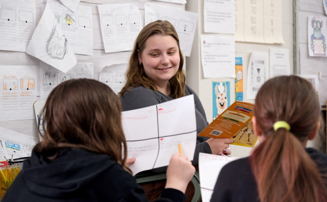 Student teaching at McKay reading to two female students.