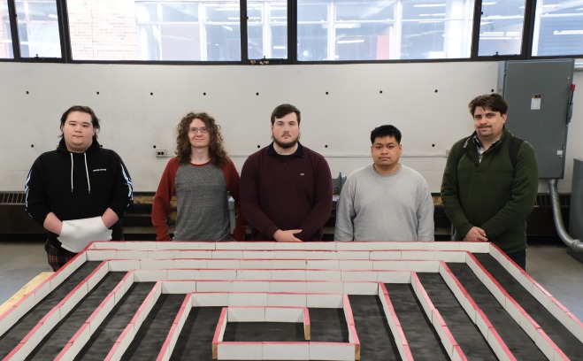 Engineering students in front of their micro mouse winning project