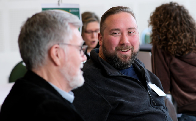 Smiling male student looking and talking with Michael Greenwood