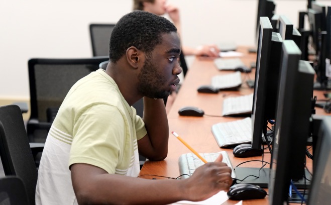 Male student at computer with pencil and paper