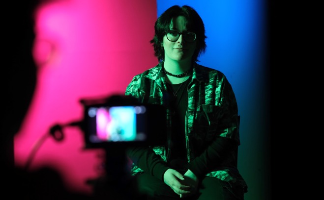 Student taking photo of student with colored lighting