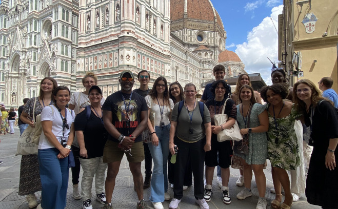 Group of students and staff in Verona Italy with white buildings in background.