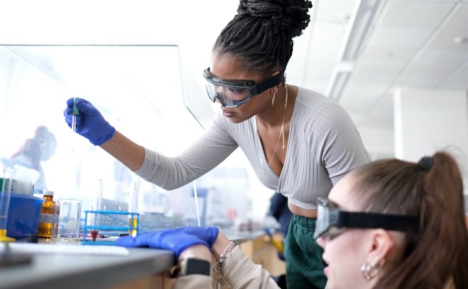 Chemistry students filling test tubes in lab.