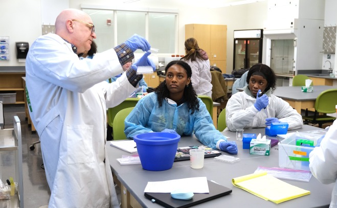Teacher demonstrating to students how to do the experiment in the lab.