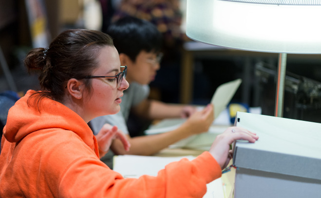 Female student in archives opening box.