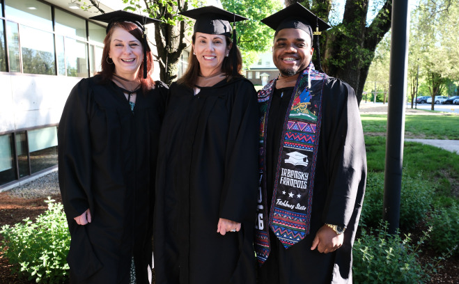 Smiling graduate students in front of science building.