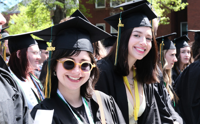 Smiling undergrad students on quad at commencement.