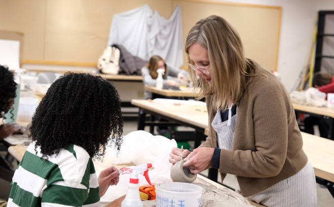 Student and teacher in visual arts pottery class.