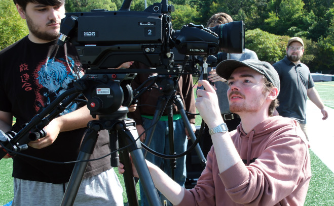 Male students filming at Elliot Field.