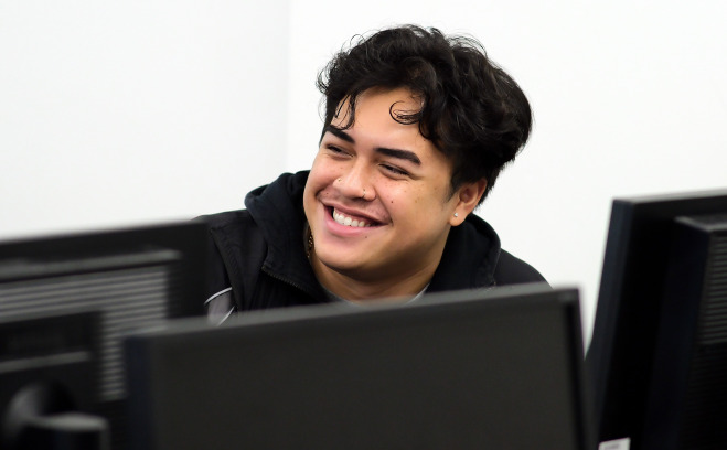 Smiling engineering tech student in classroom behind computer.