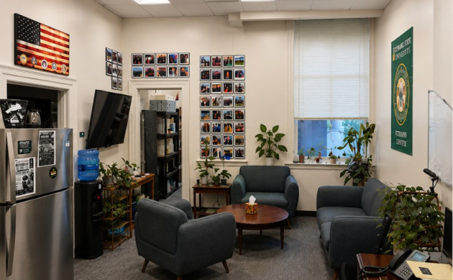 Veteran center lounge space with couches, tv, refrigerator, water, work station. 