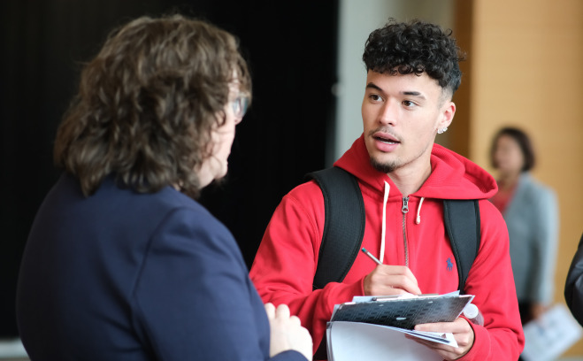 Student talking to CSA staffer at graduate fair.