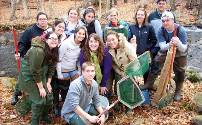 A group of Environmental Biology students standing next to a river and holding nets