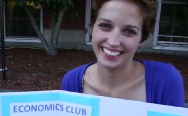 Student with a poster for the Economics Club