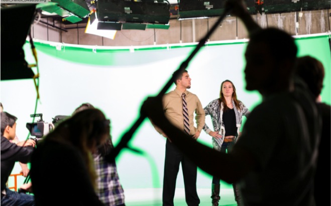A man and woman being photographed a green screen
