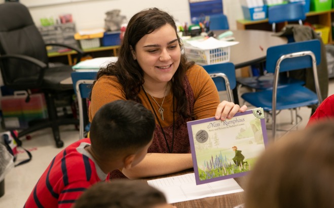 Student teacher in McKay classroom with students and book