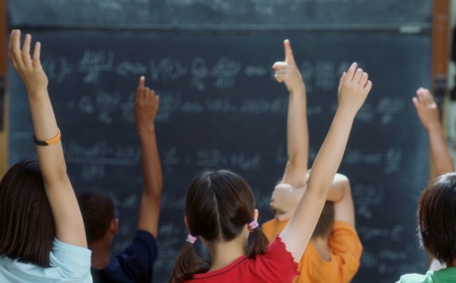 young students with hands raised
