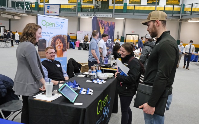 Male and female student talking to employers at booth at career fair in rec center