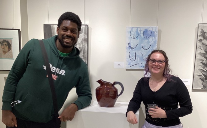 Male and female student next to sculpture in art gallery