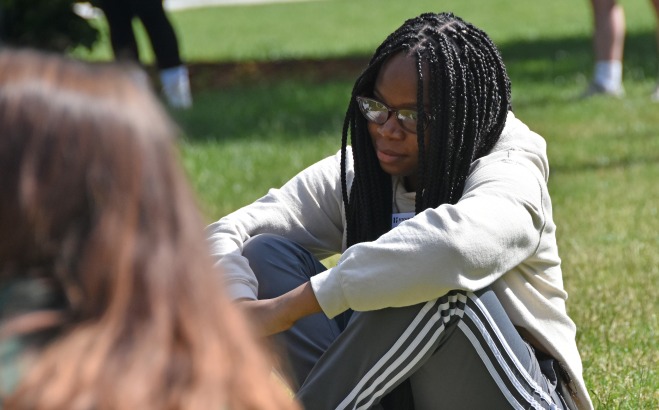 Student on quad at orientation sitting in grass