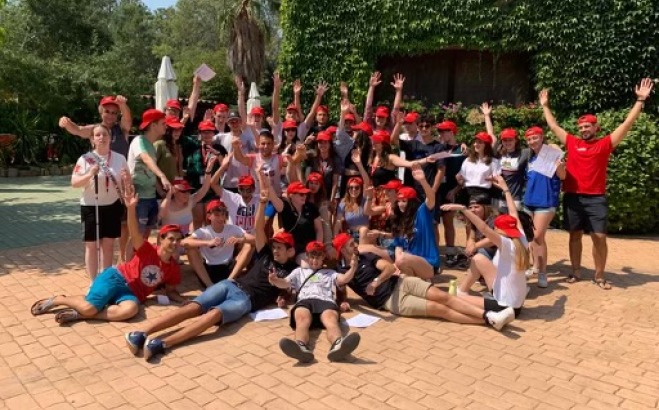 Group photo in front of ivy building with red hats on