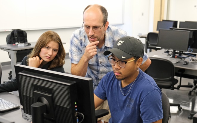 Male teacher with students at computer