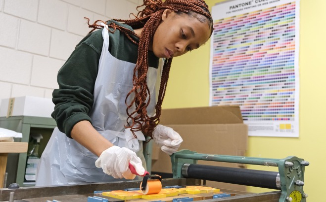 Female student in printmaking typography class working with a printing press