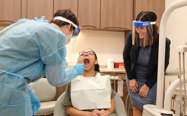 Monty Tech dental classroom students evaluating teeth in dental chair and principal looking on