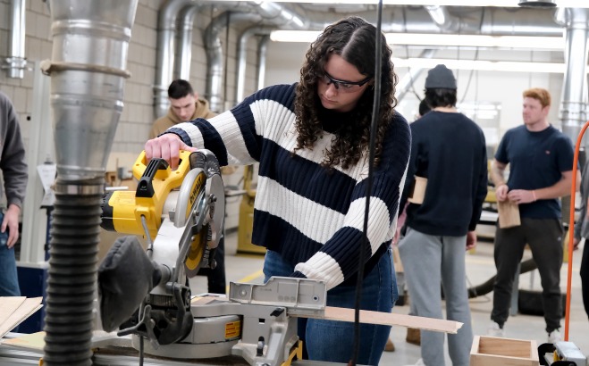 Female student using saw in design and fabrication class