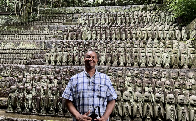 Shariff in Japan in front of a statue wall