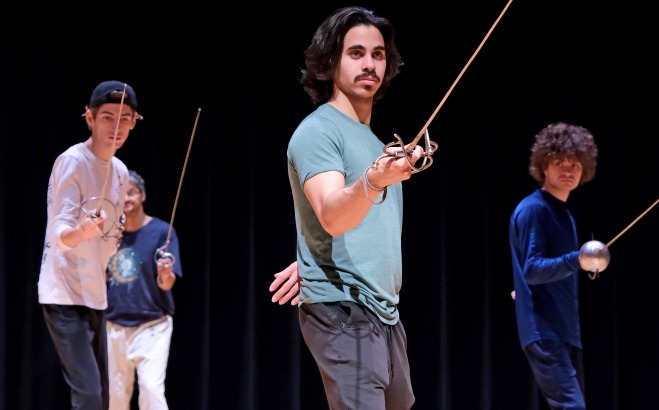 Male students in Weston theater doing sword fighting 