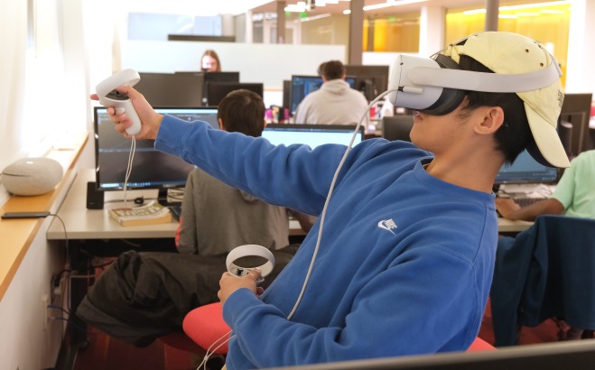 Student with VR goggles and controller in class