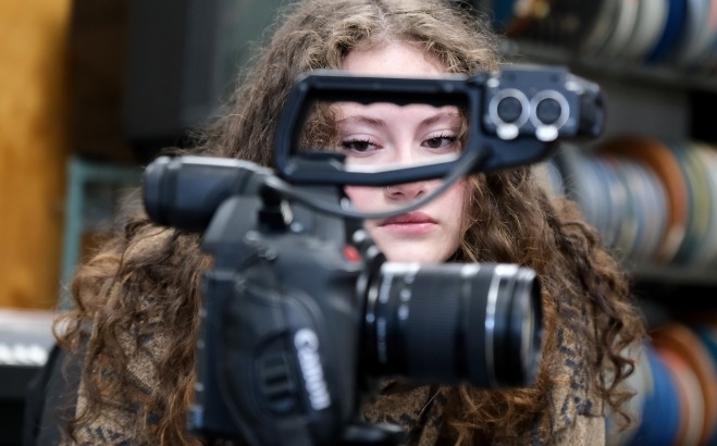 Female behind the camera with all film containers behind her