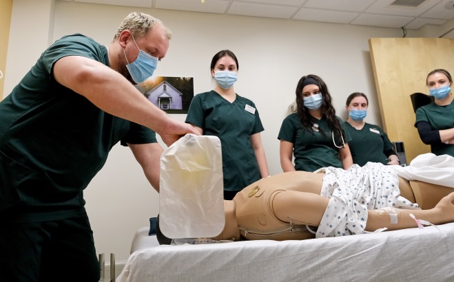 Male nursing student working on "patient" in sim lab