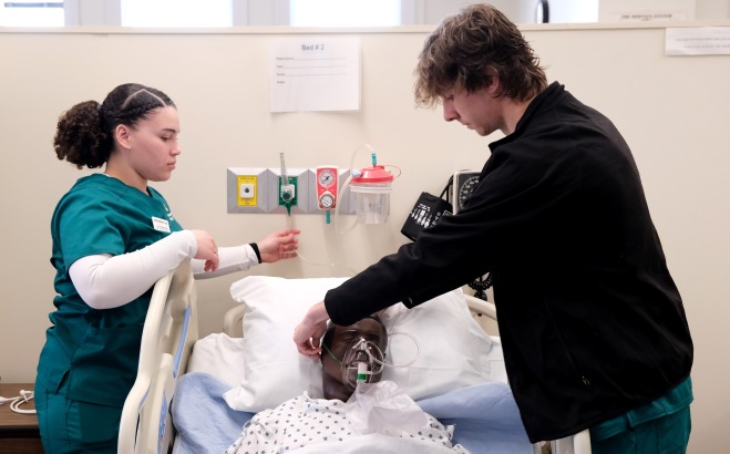 Male and female nursing students giving patient oxygen