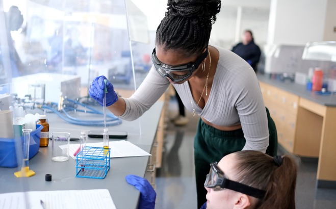 Students putting chemicals in test tubes in lab