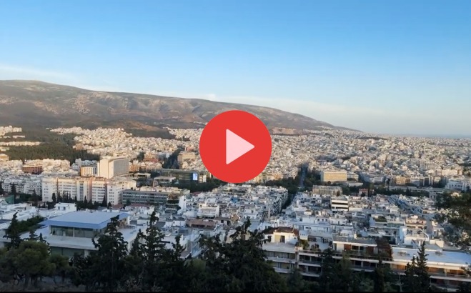 Greek town from above with video play button over it