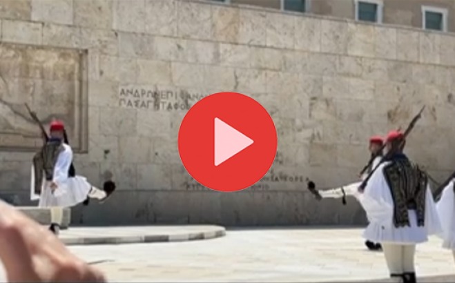Play button over guards marching in Greece