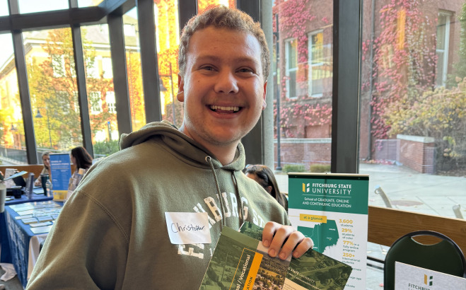 Chris Bjornson in main lounge at career fair smiling holding flyer.