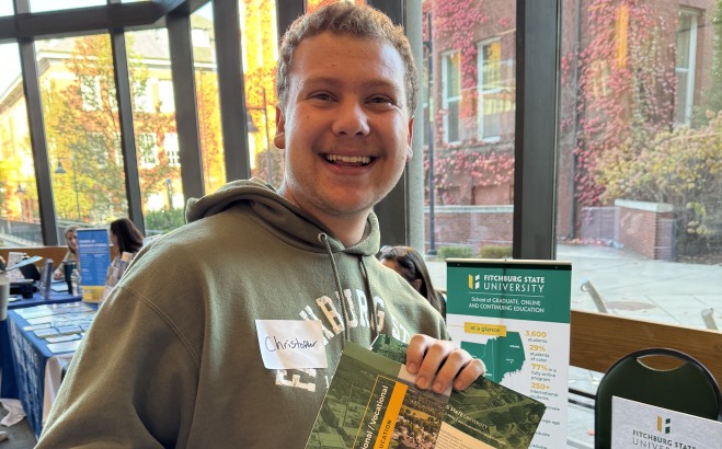 Chris Bjornson in main lounge at career fair smiling holding flyer